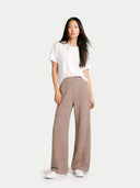 Woman wearing a white t-shirt and brown wide pants on a white background #color_taupe
