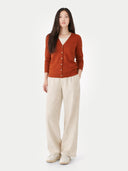 front view of a woman wearing a rust-colored cardigan and beige pants on a white background #color_sugar-almond