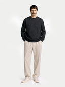 front view of a man wearing a dark sweater and light pants on a white background #color_charcoal