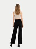 back view of Woman wearing a beige top and black pants on a white background #color_off-white