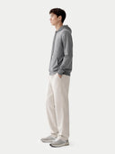 Person standing sideways wearing a gray hoodie and beige pants on a white background #color_dim-gray