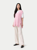 Woman wearing a pink top and white pants on a white background #color_almond-blossom