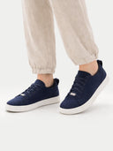 Navy blue sneakers with white soles worn with beige pants on a light gray background  #color_navy
