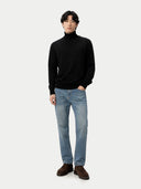 front view of a man wearing a black turtleneck sweater and light blue jeans on a white background #color_black