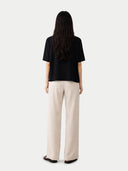 back view of Person wearing a black top and beige pants on a white background #color_black