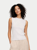 Woman wearing a white sleeveless top and beige pants on a light gray background #color_whisper-white