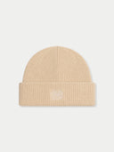 A beige ribbed knit beanie hat with a folded cuff and a small white embroidered logo on the front, shown against a light gray background.