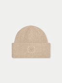 A beige ribbed knit beanie hat with a folded cuff and a small tonal embroidered logo in the center, shown against a light gray background.