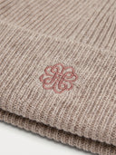 Close-up of the Unisex Seamless Cashmere Ribbed Beanie in Taupe, showing the rib knit and the embroidered monogram on the turn-up cuff