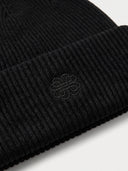 Close-up of the Unisex Seamless Cashmere Ribbed Beanie in Black, showing the rib knit and the tonal embroidered monogram on the turn-up cuff