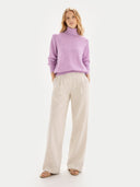 Woman wearing a purple sweater and beige pants on a white background #color_fuchisa-pink