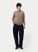 front view of a person wearing a brown zip-up sweater and black pants on a white background. #color_taupe