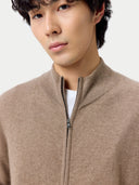 Close up of a man wearing a beige zip-up sweater against a plain background. #color_taupe