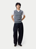 Person wearing a gray v-neck vest over a white shirt with black pants on a white background #color_dim-gray