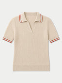 A short-sleeve ribbed knit polo shirt in cream with red stripes on the collar and sleeve cuffs, shown flat against a light gray background.
