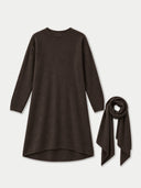 A dark brown long-sleeve knit dress with an asymmetrical hem, shown next to a matching dark brown scarf on a light gray background.