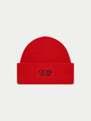 A bright red ribbed knit beanie hat with a folded cuff, featuring the black embroidered text 'GOBI EST. 1981' on the front, set against a light gray background.