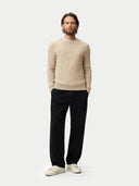 Man wearing a beige sweater and black pants on a white background #color_warm-grey