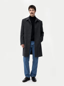 front view of a man wearing a black coat, black sweater, and blue jeans on a white background #color_charcoal