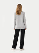 back view of a woman wearing a light gray sweater and black pants on a white background #color_high-rise