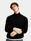 Man wearing a black quarter-zip sweater and beige gloves on a light gray background #color_beige