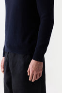 Person wearing a dark blue sweater and black pants on a white background #color_navy-blazer