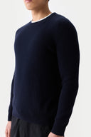 Person wearing a navy blue sweater on a light gray background #color_navy-blazer