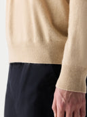 close up of a beige sleeve of sweater and black pants. #color_beige