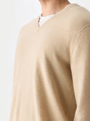 close up of a beige v-neck sweater worn by a person on a light gray background #color_beige