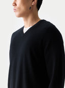 close up of a person wearing a black v-neck sweater over a white t-shirt on a white background #color_black 