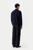 back view of a man wearing a dark blue mock neck cardigan and black pants on a white background #color_navy blazer