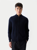 close up of a man wearing a dark blue zip-up cardigan on a light gray background #color_navy-blazer