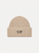 A beige ribbed knit beanie hat with a folded cuff, featuring the black embroidered text 'GOBI EST. 1981' on the front, set against a light gray background.