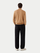 back view of Person wearing a beige sweater and black pants on a white background #color_sheepskin