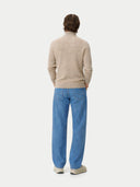 Back view of a person wearing a beige sweater and blue pants on a white background #color_warm-grey