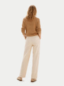 Woman wearing a brown sweater and beige pants on a white background #color_almond