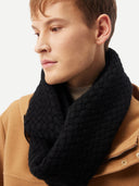 Man wearing a black knitted scarf with a plain background #color_black