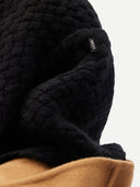 Close-up of a textured black fabric with a brand label on a white background #color_black