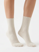 Cashmere rib-knit socks in Warm Light worn by a model, mid-calf length, side view