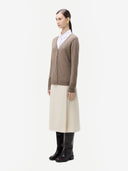 side view of a woman wearing a brown cardigan, white shirt, beige skirt, and black boots on a white background #color_taupe
