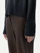 side view of a person wearing a dark gray zip-up cardigan with ribbed cuffs, hem and brown pants #color_charcoal