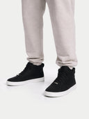 Black high-top sneakers worn with light gray sweatpants on a white background #color_black