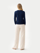 back view of a woman wearing a navy long-sleeve top and beige pants on a white background #color_navy