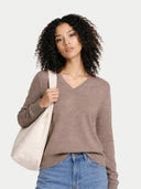 front view of a woman wearing brown v neck sweater and holding a beige tote bag against a white background #color_taupe