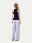 back view of Woman wearing a navy sleeveless top and light purple pants on a white background #color_navy