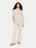 Woman wearing a beige turtleneck sweater and pants on a white background #color_dawn-blue