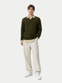 Man wearing a green v-neck sweater, beige shirt, white pants, and white sneakers on a white background #color_avocado