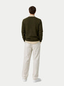 back view of a man wearing a green sweater and white pants on a white background #color_avocado