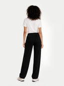 back view of a woman wearing a white t-shirt and black pants on a white background #color_black