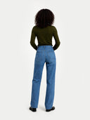 back view of a person wearing blue jeans and a green top on a white background #color_avocado